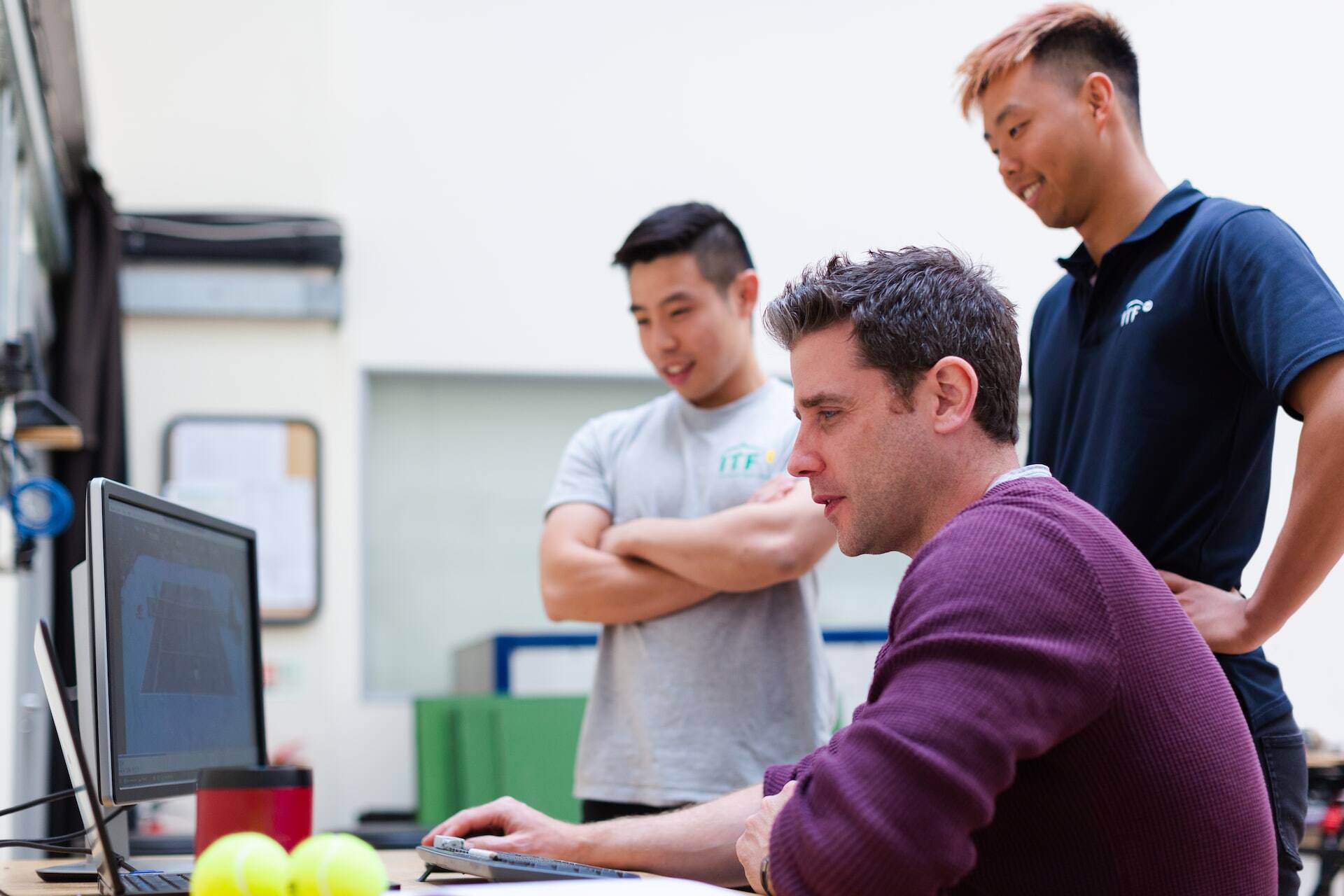 three man looking to a computer