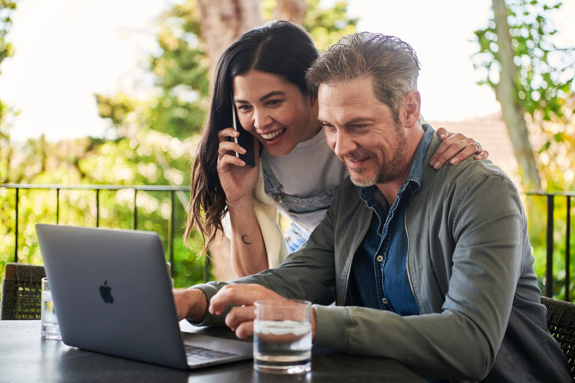 Woman speaking in a smartphone and looking at something with a man in a computer