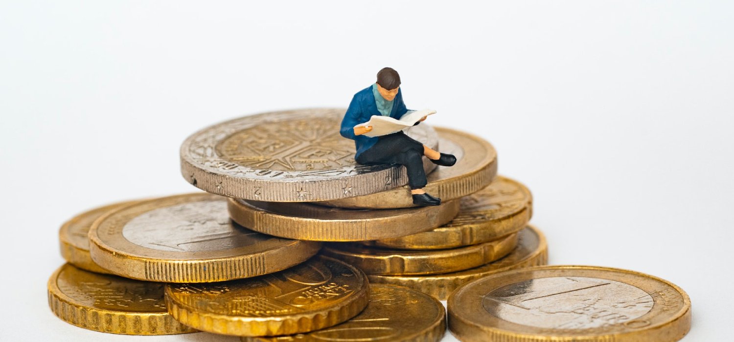 Doll sitting in coins reading a book