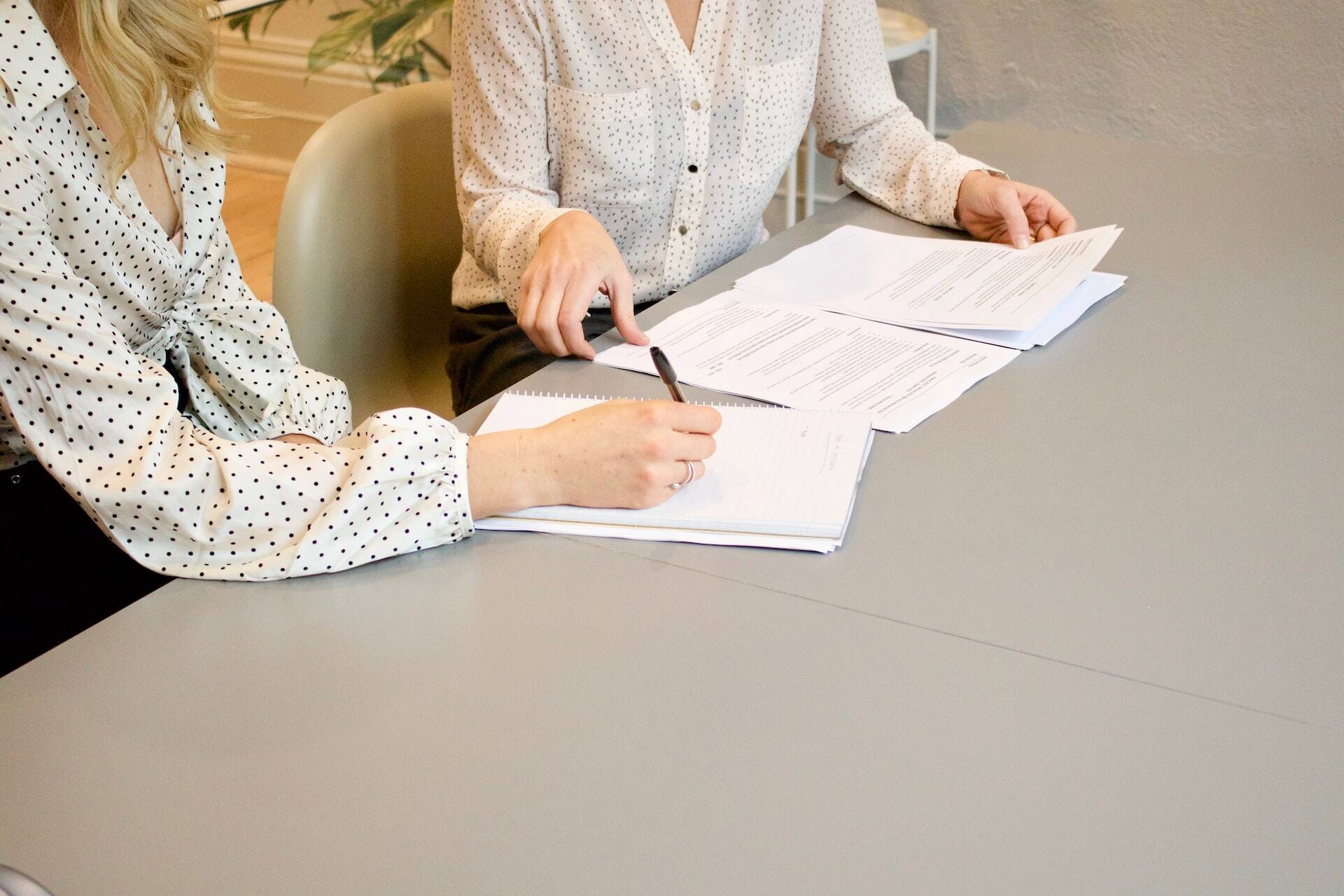 Two women reading some papers and taking notes