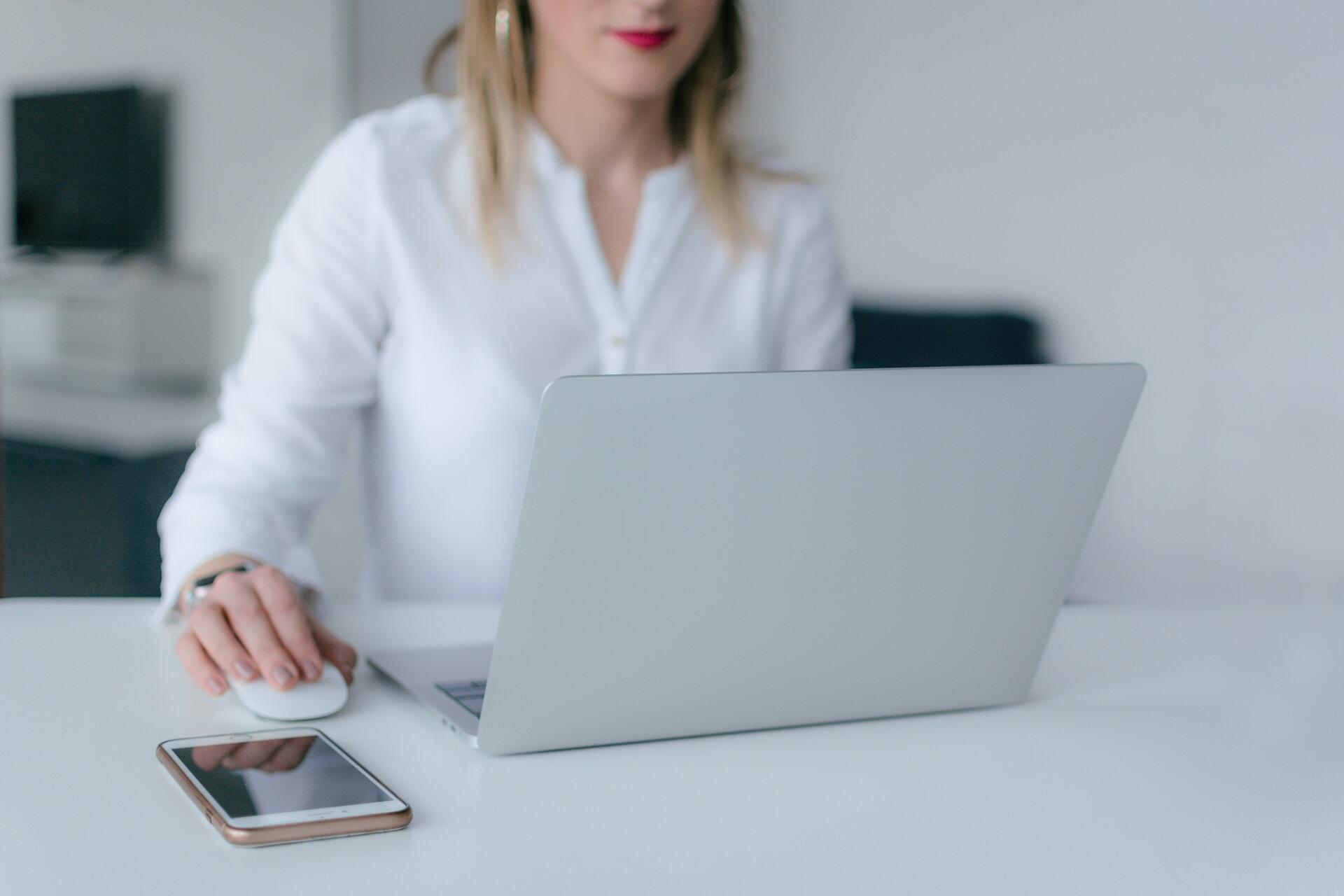 Woman working in a notebook with a smartphone by her side