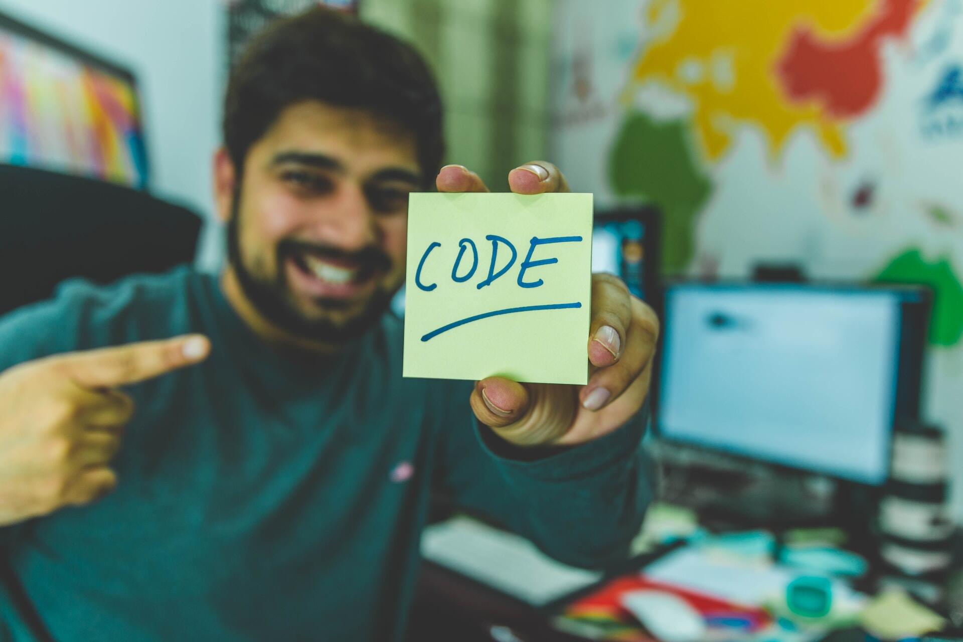 Man showing a post it with code written on it