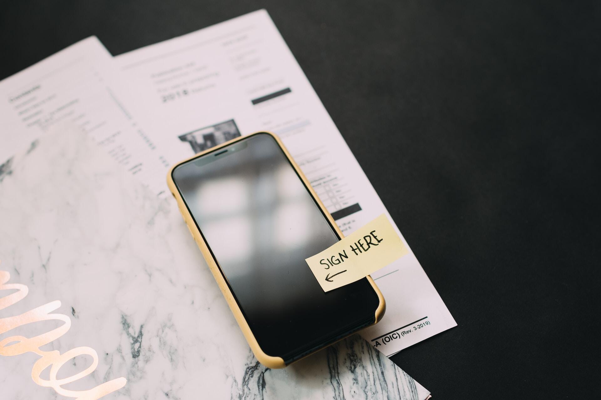 Smartphone with a post-it with the message sign here