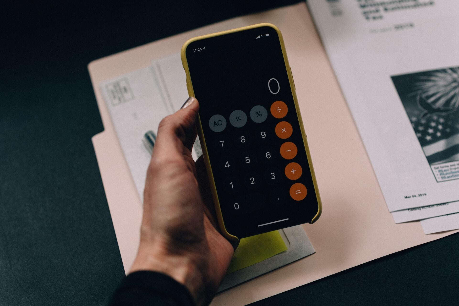 Woman hand holding a smartphone using the calculator app